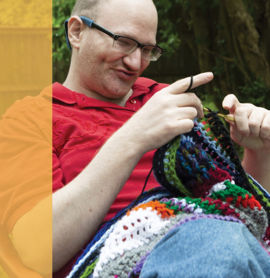 Photo of Brandon Cantrell knitting in a chair.