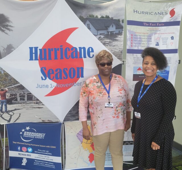 Photo of Naomi and another African American lady standing in front of a banner that says Hurricane Season