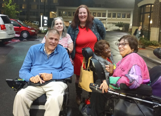 Four people posing for a photo, two people in the front are wheelchair users