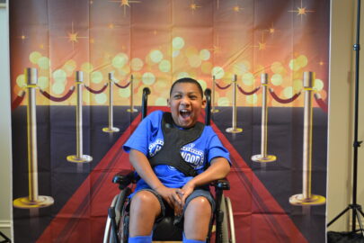 Picture of a young boy in a wheelchair smiling