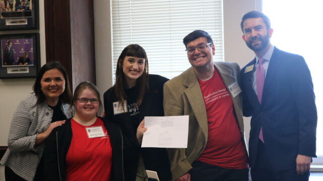A picture of Destination Dawgs members Alexis Szelwach, Hallie McCollum, Liza Crane, and Ben Harrison with Rep. Houston Gaines holding up a copy of the bill HB185 in Rep. Houston Gaines' office.