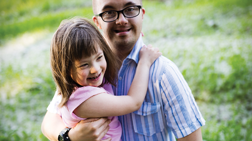 Caucasian man holding a younger caucasian girl in his arms.